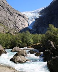 Scenic view of stream flowing through rocks against sky