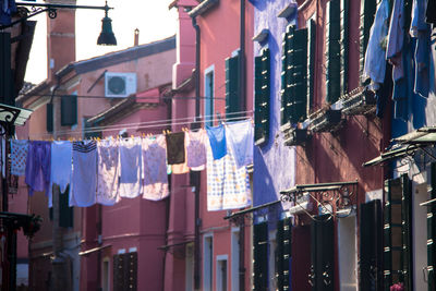 Low angle view of clothesline between buildings in city