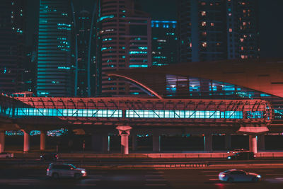 Cars on road by illuminated buildings in city at night