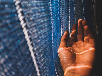 Cropped hand of woman against blinds at home