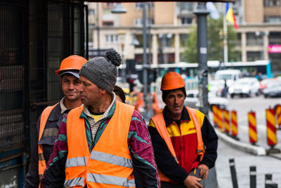 Portrait of friends standing against orange wall