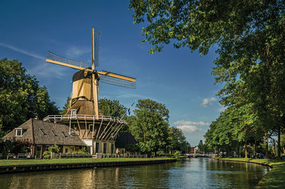 Traditional windmill by lake against sky