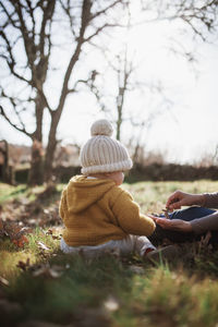 Mother and daughter wearing warm clothing while sitting on land