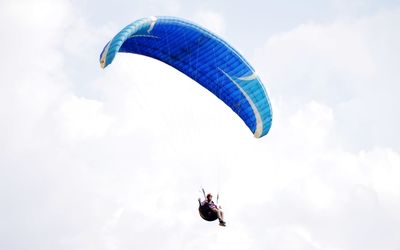 Low angle view of person paragliding against sky