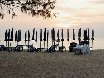 Chairs on beach against sky during sunset