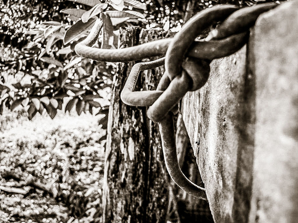 CLOSE-UP OF RUSTY METAL HANGING ON METALLIC STRUCTURE