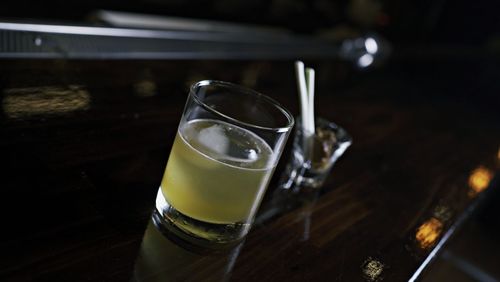 A glass of golden liquid in a whiskey glass on the bar