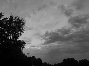 Low angle view of silhouette trees against cloudy sky