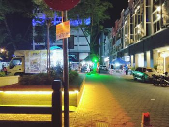 Illuminated street amidst buildings in city at night