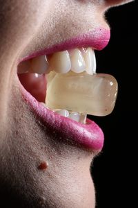 Extreme close up of woman holding ice cube in mouth