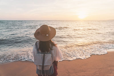 Woman standing on beach against sky during sunset