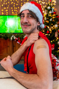 Portrait of a young male smiling after getting a vaccine - man showing her arm with bandaid