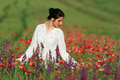 Young woman with poppy flowers in field