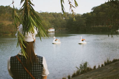 Rear view of women on lake against trees