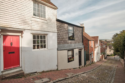 View down historic cobbled keere street with bright red front door in foreground lewes sussex uk