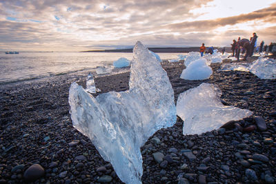 Icebergs at sea shore against sky