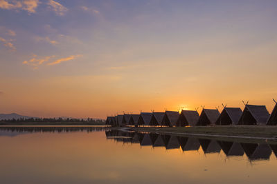 Scenic view of lake by huts during sunset