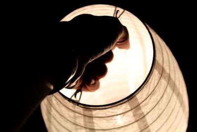 Close-up of human hand on illuminated lamp