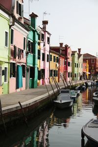 Boats moored in canal against buildings in city