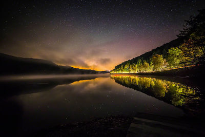 Scenic view of calm lake against mountain range at night