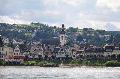 Buildings by river against sky in city