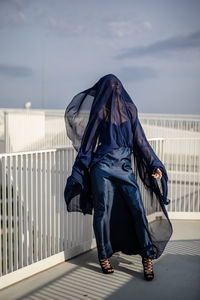 Woman in dress standing in balcony against sky