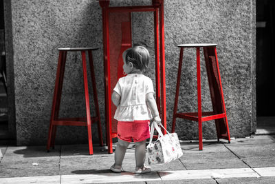 Rear view of girl standing against building