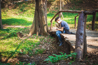 Boy sitting on footbridge in park