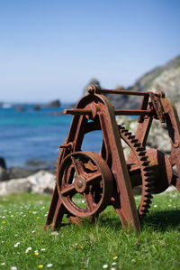 Close-up of rusty wheel on field against sky