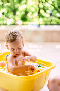 Girl with toys sitting in bathtub