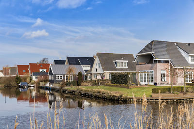 Buildings by lake against sky