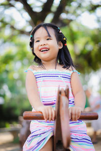 Cute girl looking away while sitting on seesaw in playground