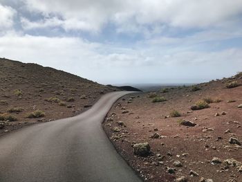 Road leading towards mountain against sky