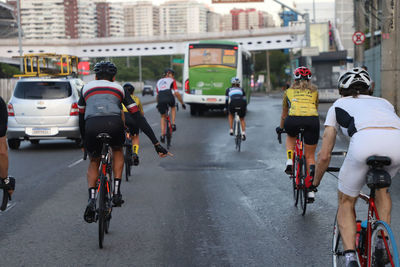 Rear view of people bicycling on road in city