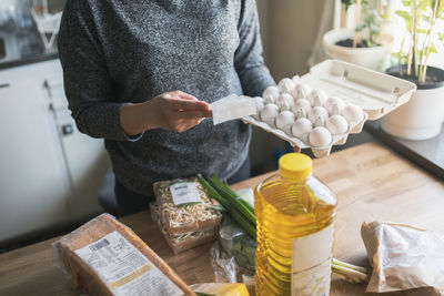 Woman checking receipt from supermarket during inflation with rise in price of food and consumer products