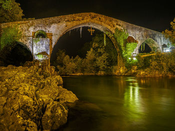 Arch bridge over river at night