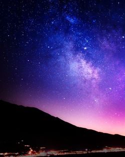 Silhouette mountain against star field at night