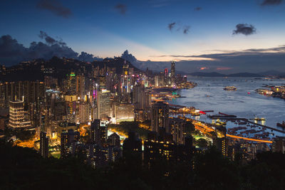 High angle view of illuminated city by sea at night