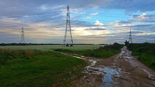 Electricity pylon on field against sky