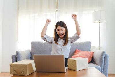 Young woman using digital tablet while sitting on sofa at home