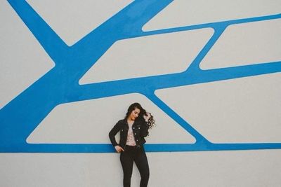 Portrait of a young woman standing against wall