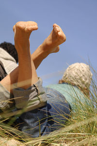 Low section of person relaxing on beach against sky