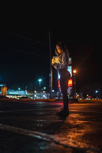 Woman standing on illuminated city against sky at night