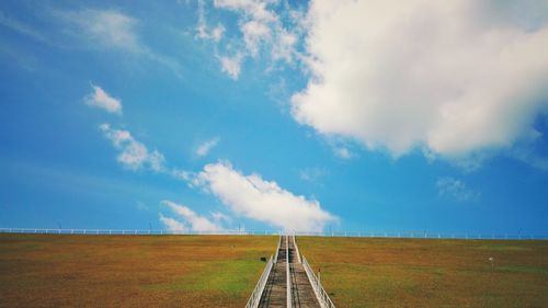 Road amidst field against sky