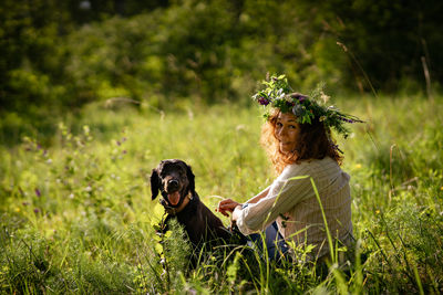 Woman enjoying digital detox and nature connection with pet in wild meadow