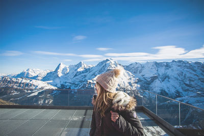 Woman at observation point against snowcapped mountains
