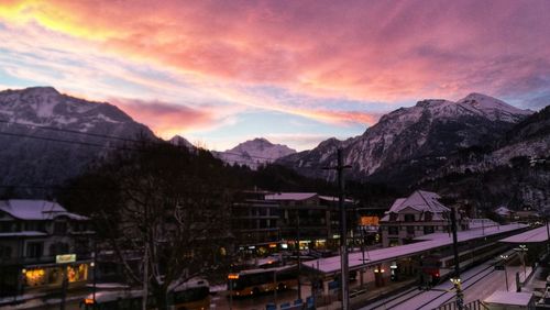 City by mountains against sky at sunset