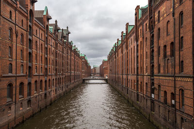 Canal amidst buildings in city against sky