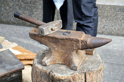 High angle view of anvil with hammer on tree stump