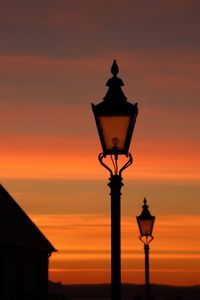 Illuminated street light against building during sunrise
